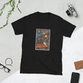 Black t-shirt printed with a vintage-style horror poster: a woman and a man with a flashlight in a burning industrial town, smoke forming a skull-like face above them, titled Where the Cinders Breathe