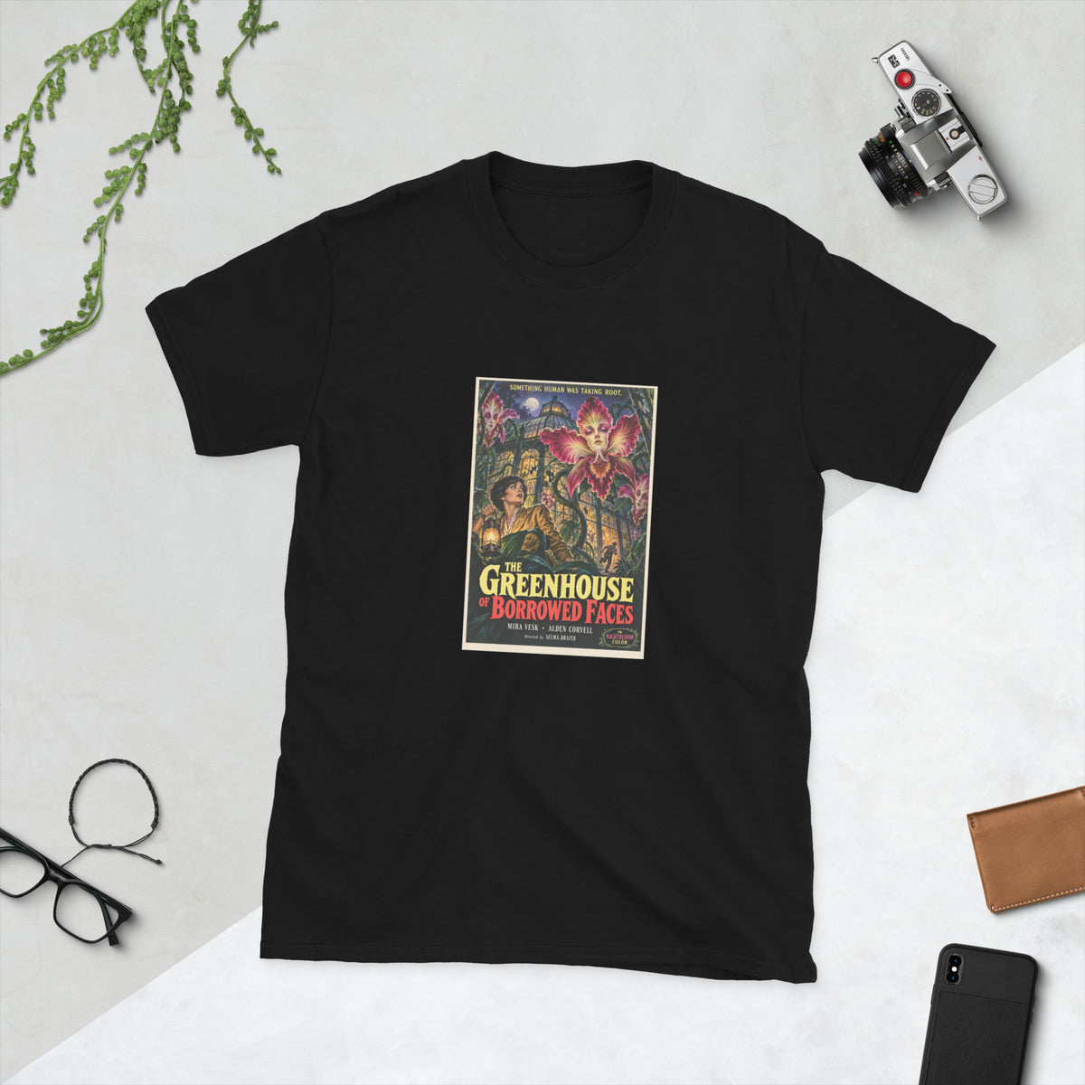 Black t-shirt printed with a vintage-style horror poster: a woman with a lantern among giant orchids with human faces inside a glass greenhouse, titled The Greenhouse of Borrowed Faces